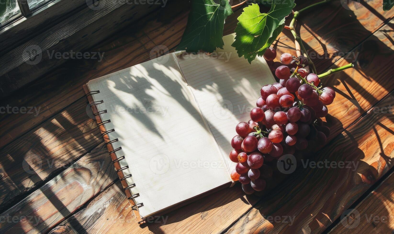 Notebook on a wooden table with a bunch of grapes photo