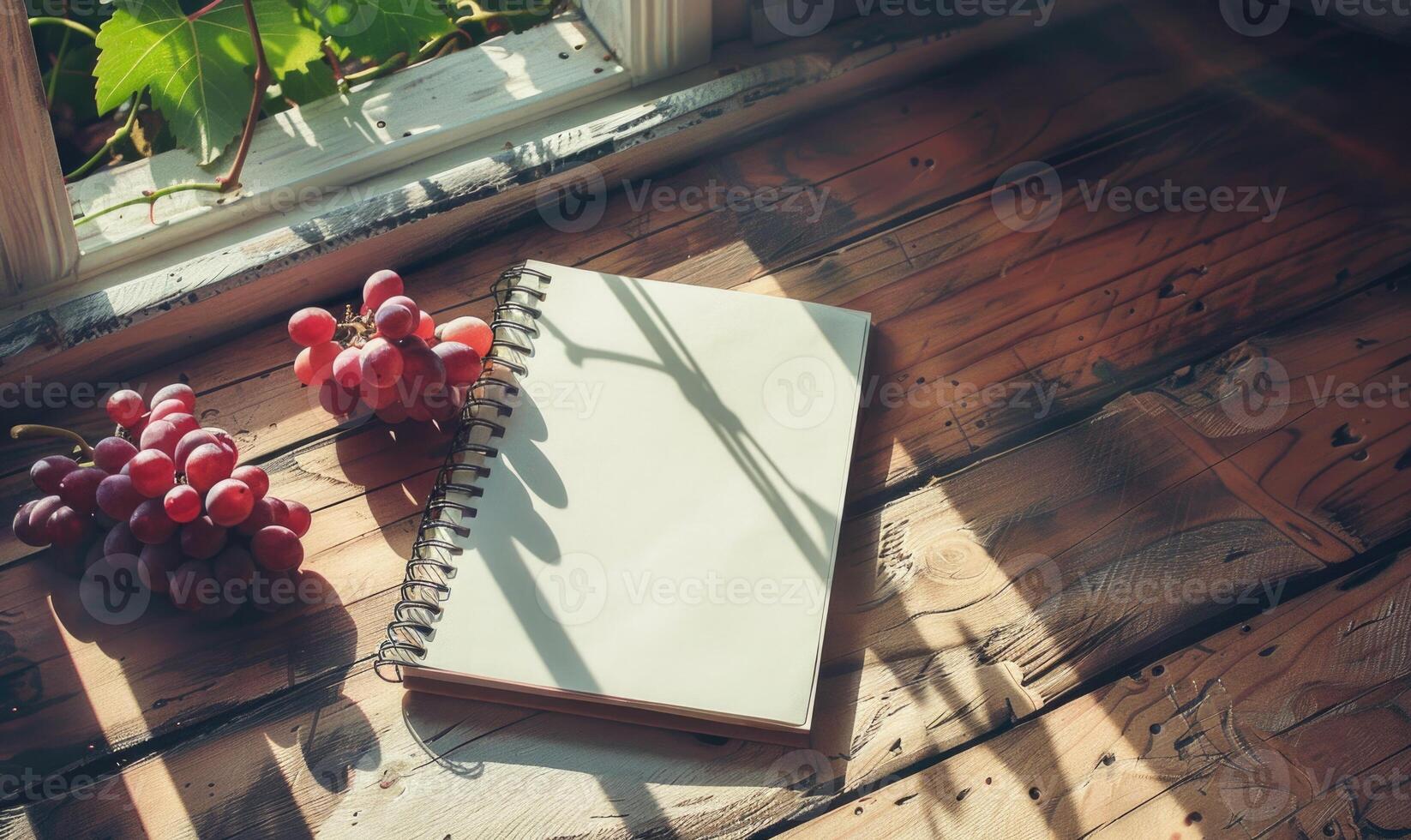 Notebook on a wooden table with a bunch of grapes photo