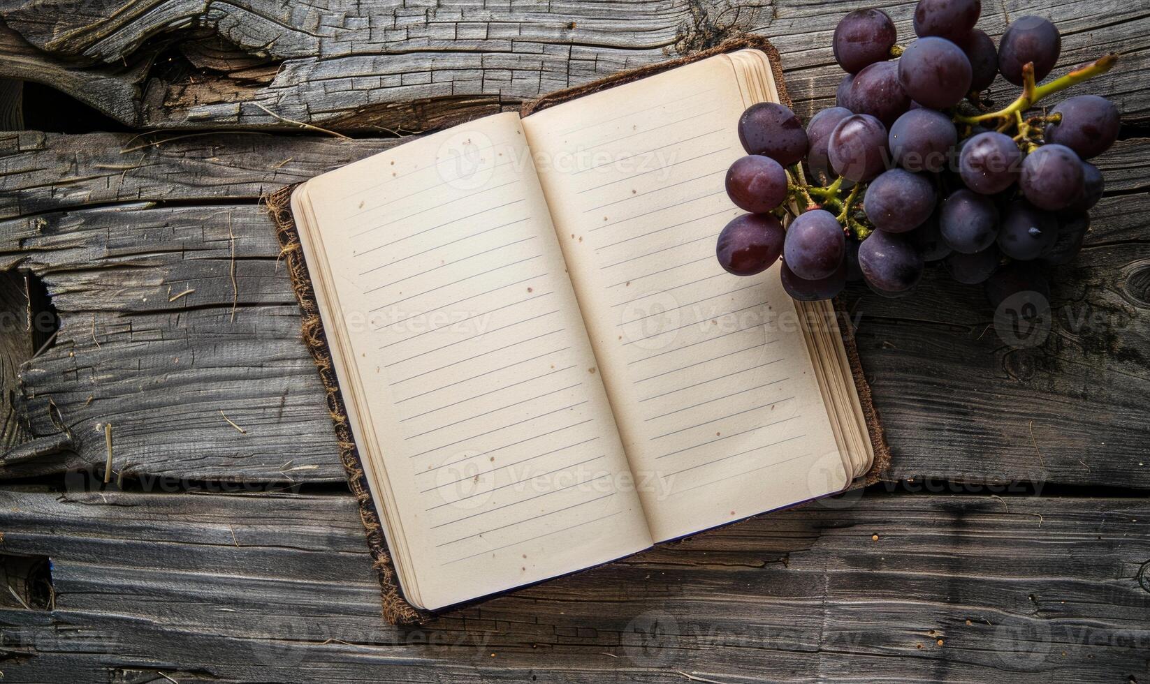 Notebook on a wooden table with a bunch of grapes photo