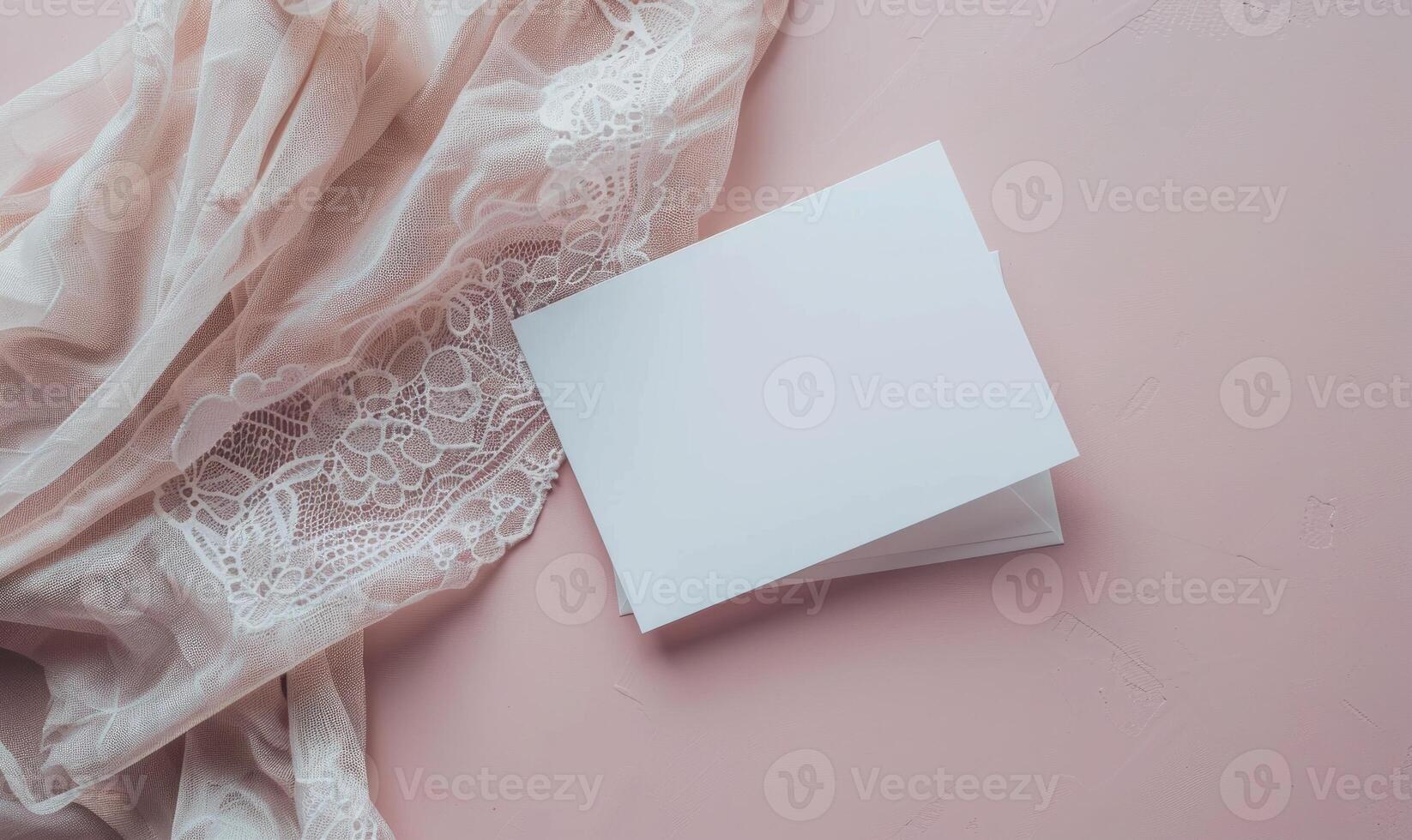 White blank card on a pastel pink table, with a delicate lace cloth photo