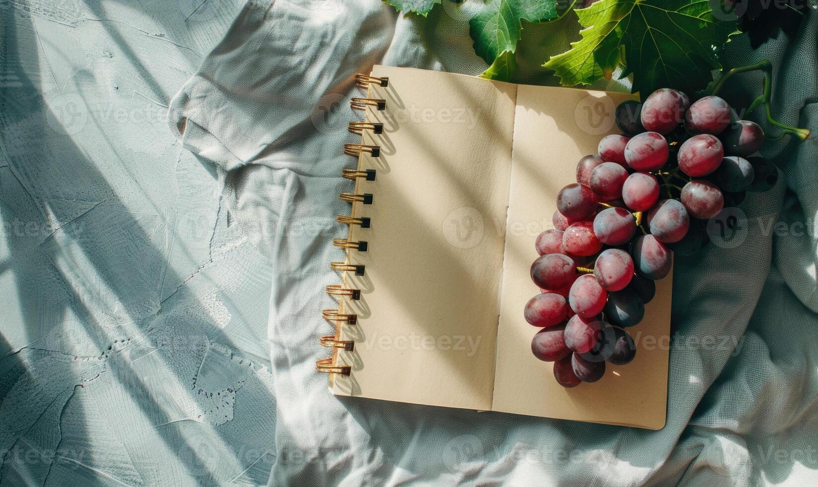Closed notebook on a light gray table with a bunch of grapes photo