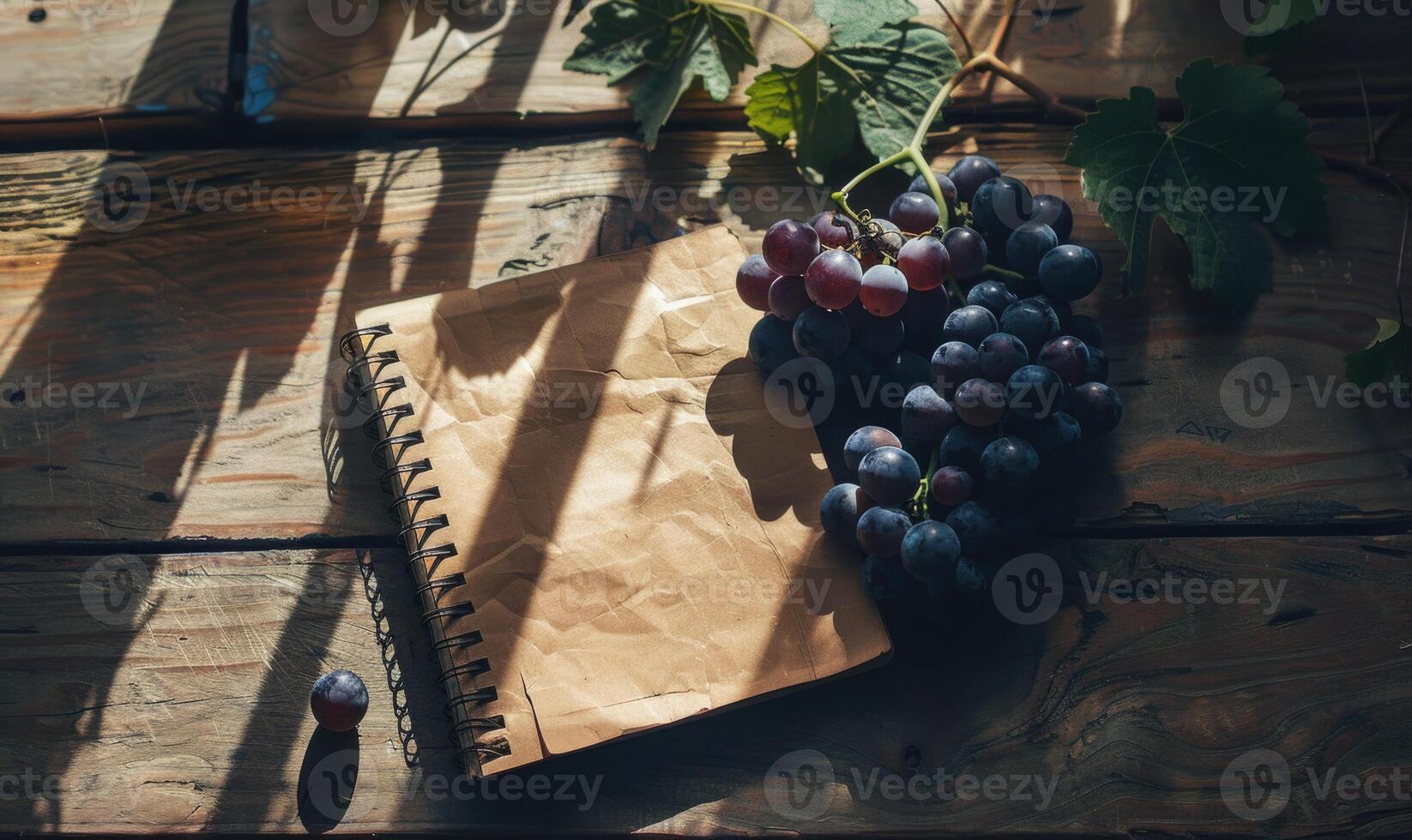Notebook on a wooden table with a bunch of grapes photo