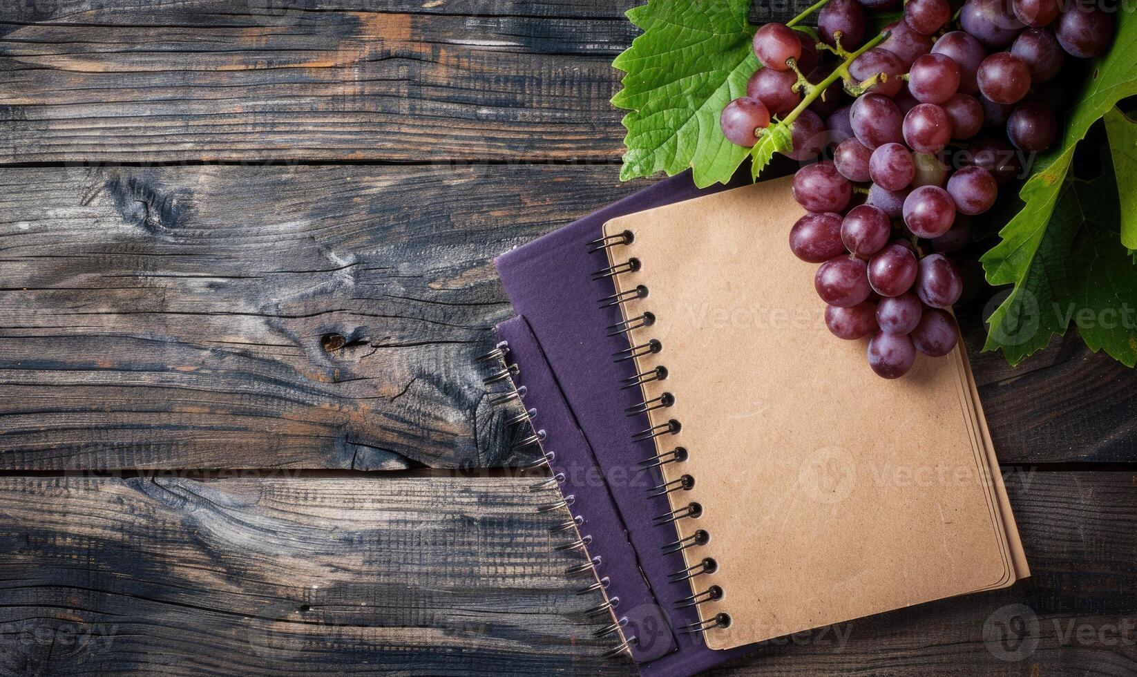 Notebook on a wooden table with a bunch of grapes photo
