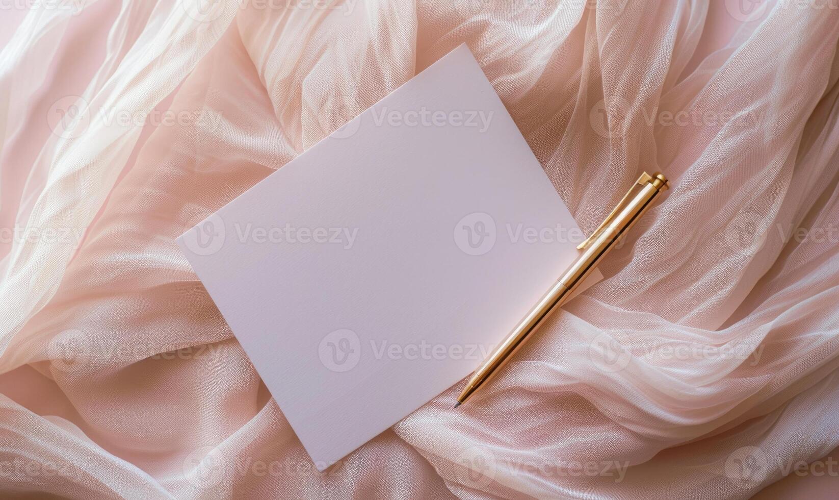 White blank card on a pastel blush pink background, with a piece of chiffon fabric and a gold pen photo