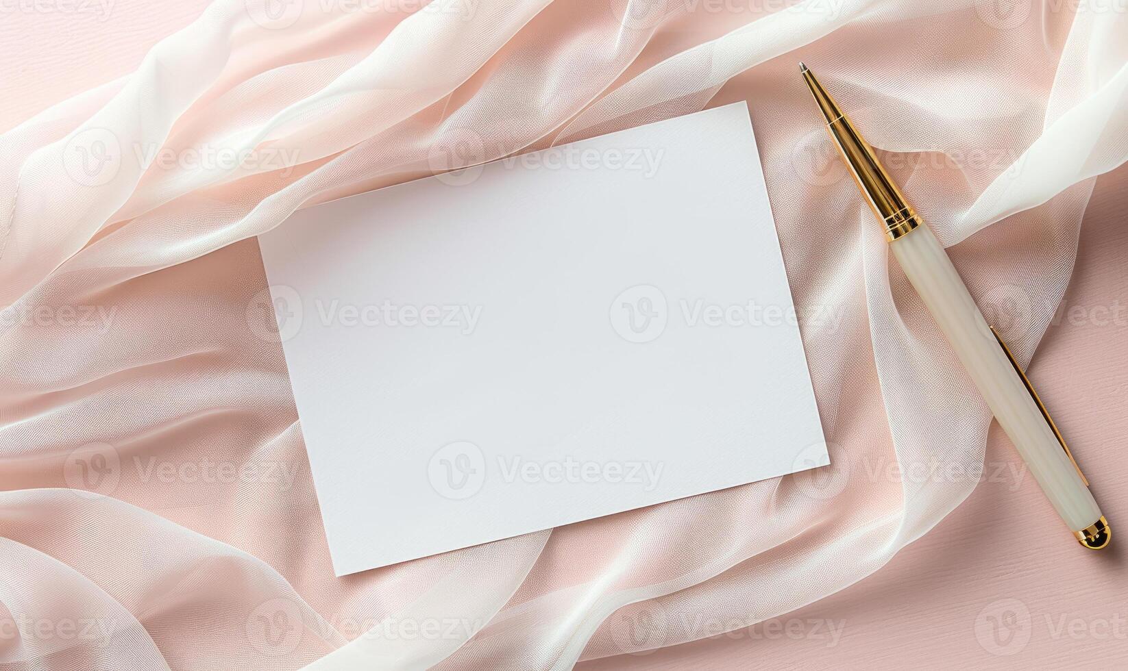 White blank card on a pastel blush pink background, with a piece of chiffon fabric and a gold pen photo
