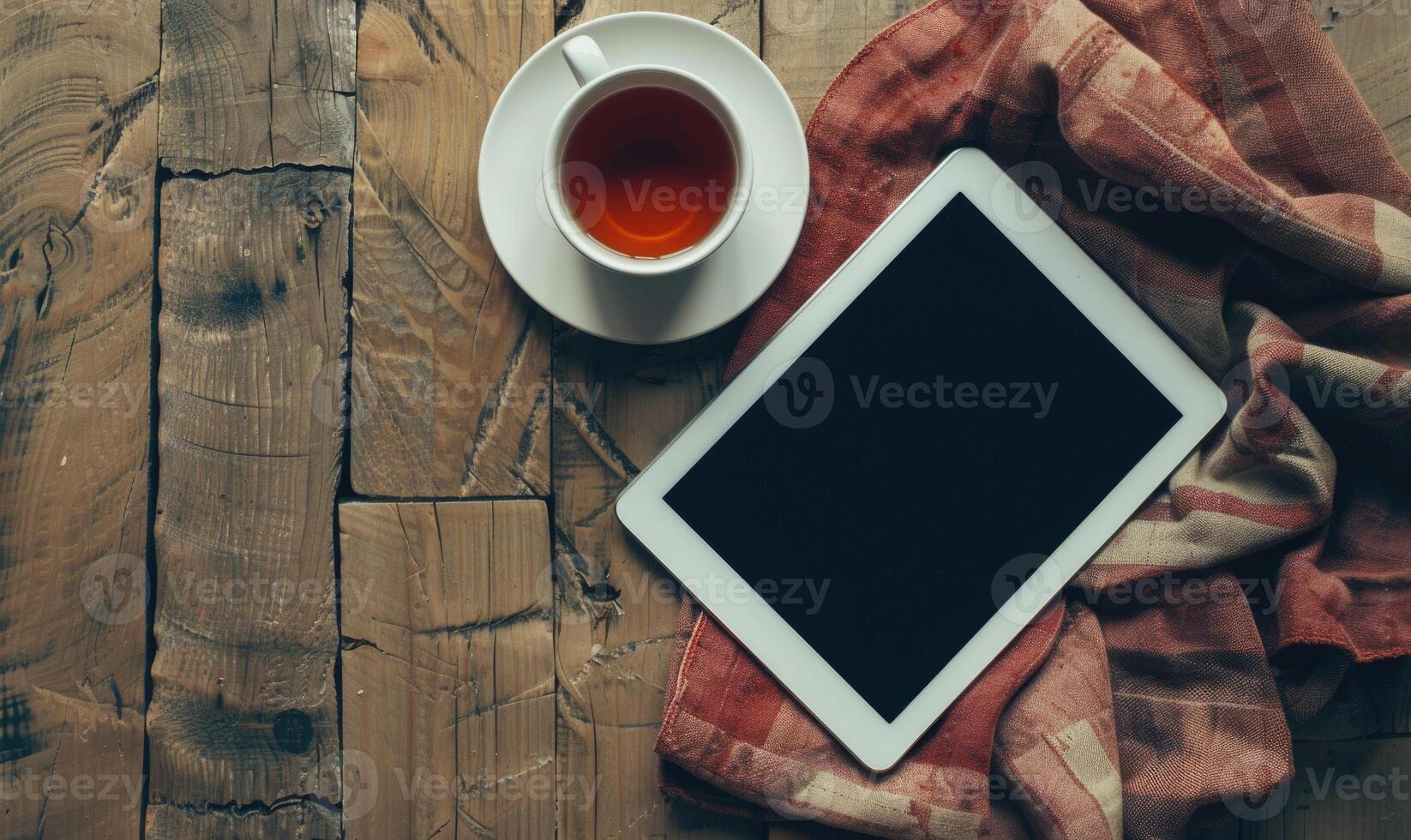 Tablet on a wooden table with a cup of coffee on the left photo