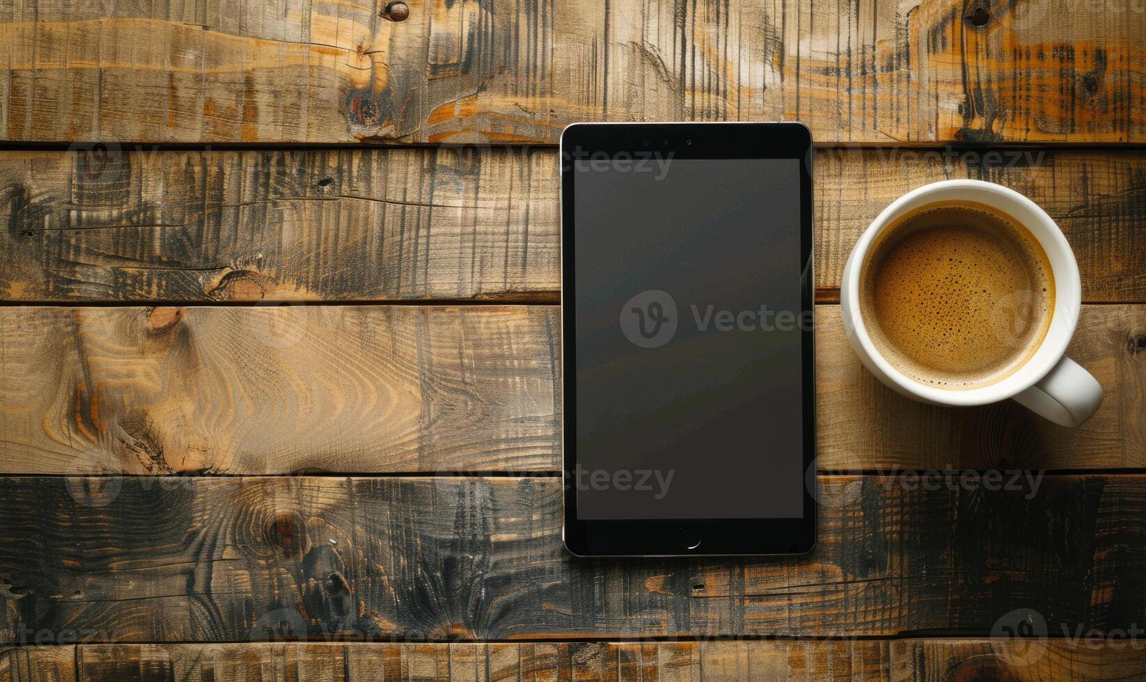 Tablet on a wooden table with a cup of coffee on the left photo
