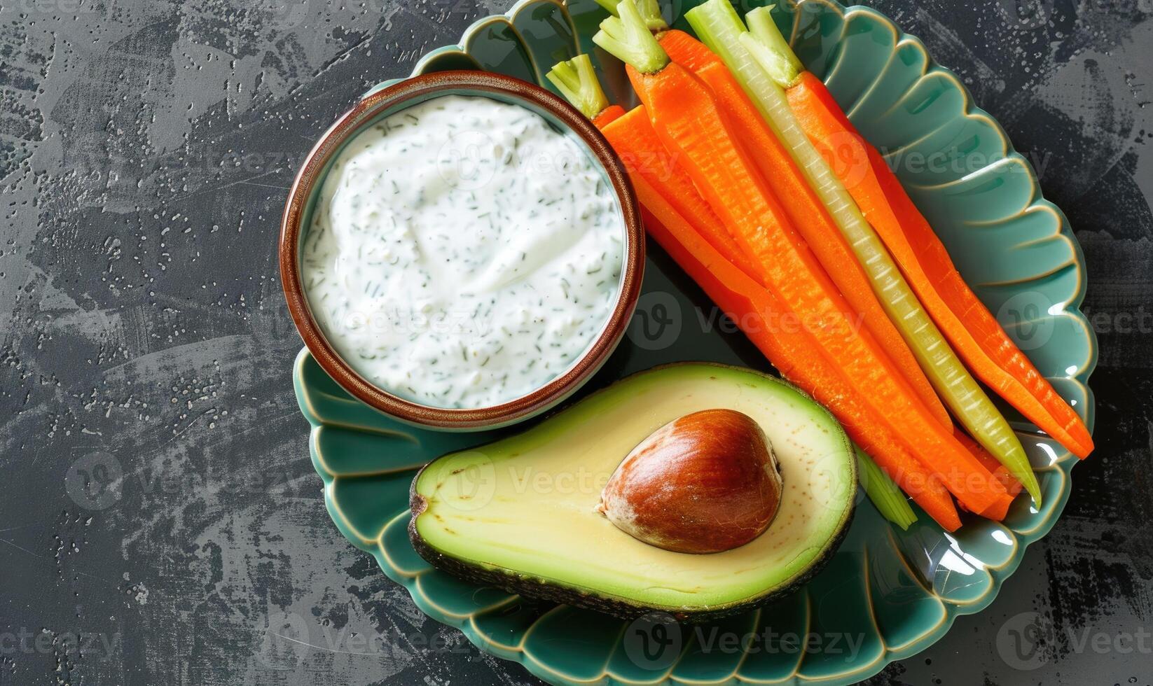 Avocado and carrot sticks with yogurt dip on a pastel green plate photo