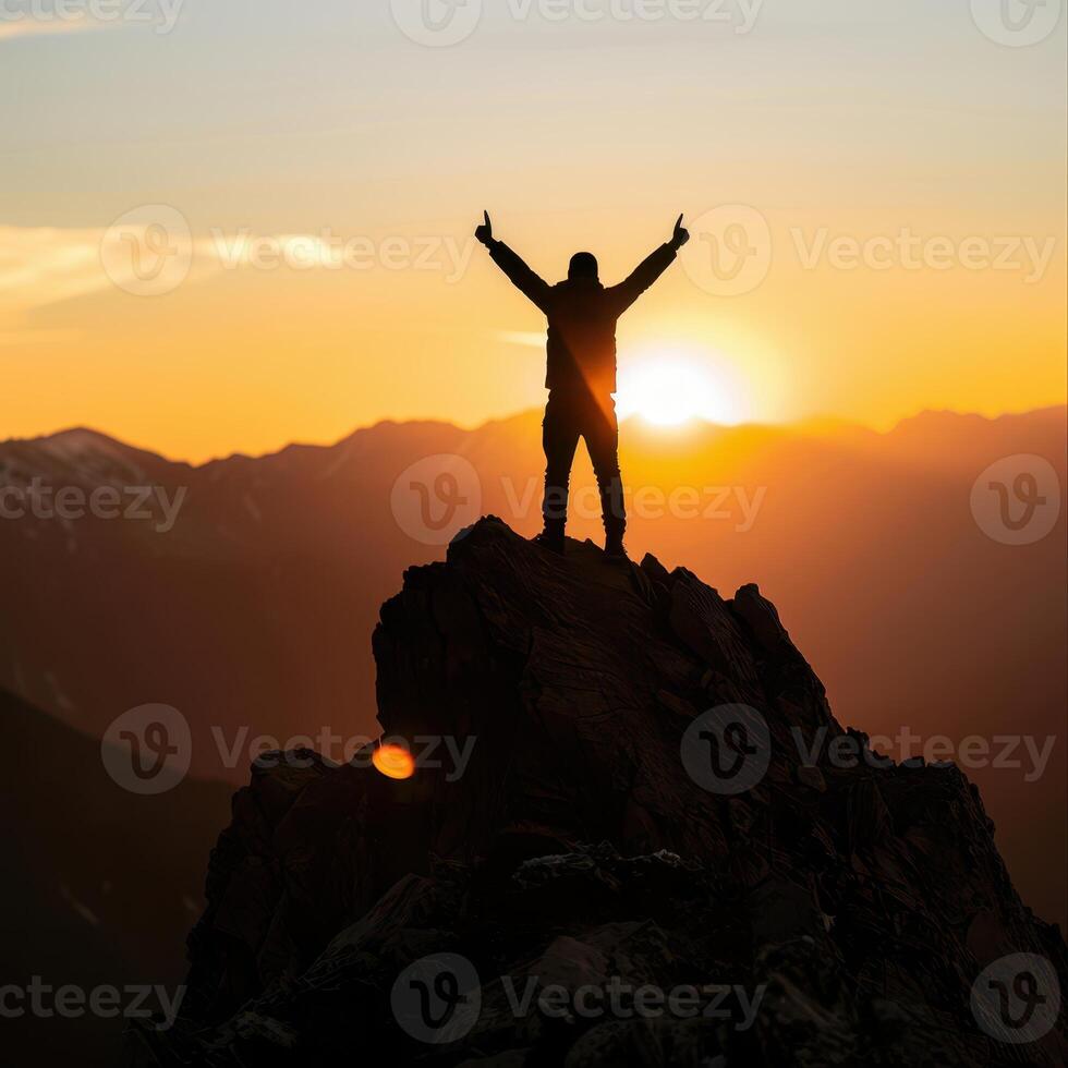 a man standing on top of a mountain with his arms raised photo