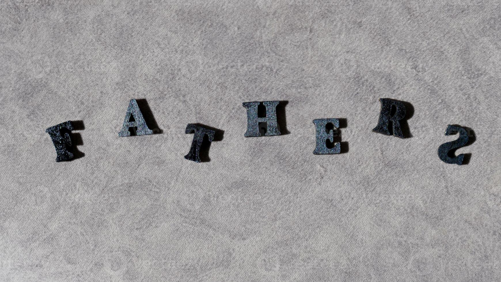 Lettering father in black letters on grey background on father's day close-up photo