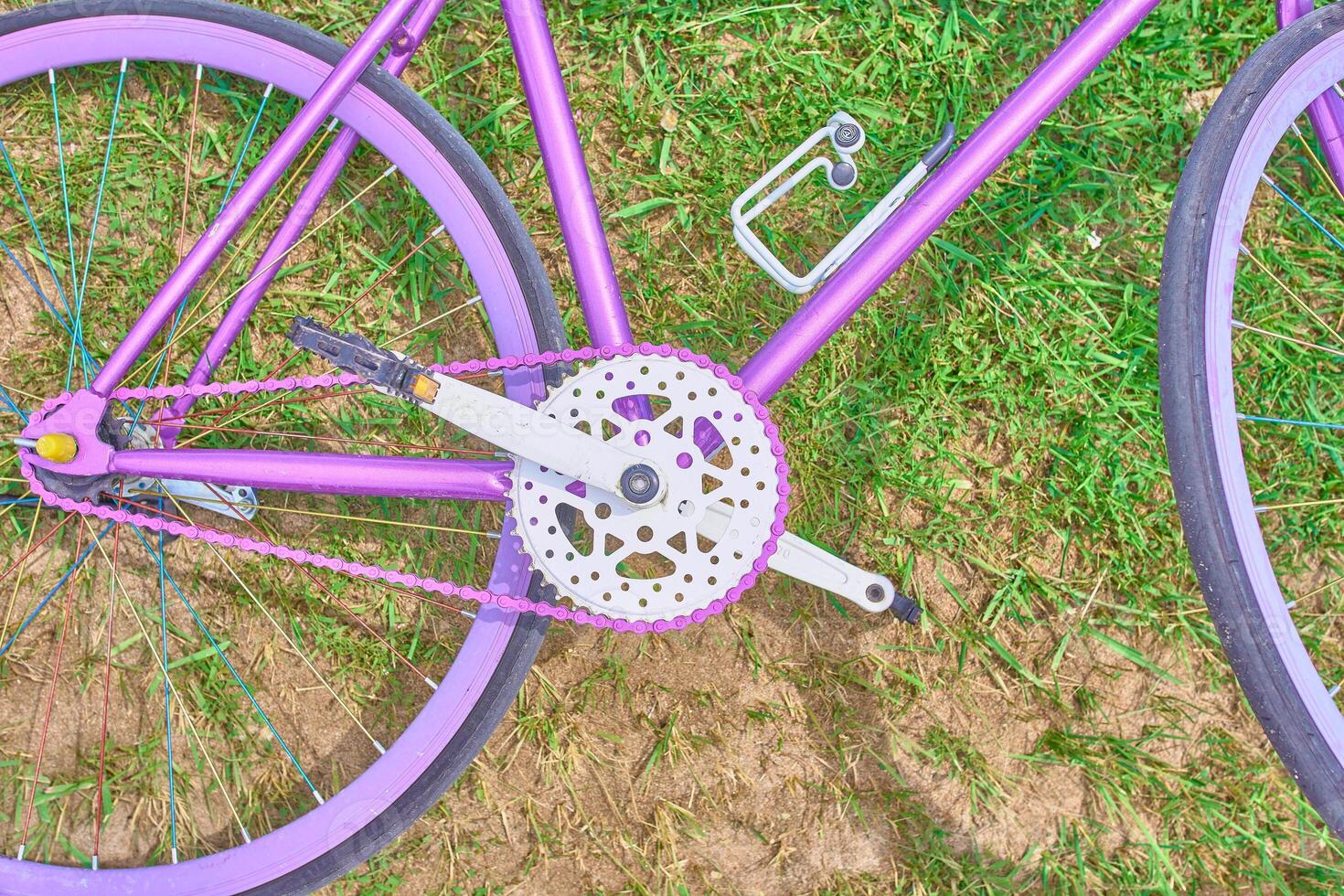 Bright pink bike lying on the grass with sand on a Sunny day photo