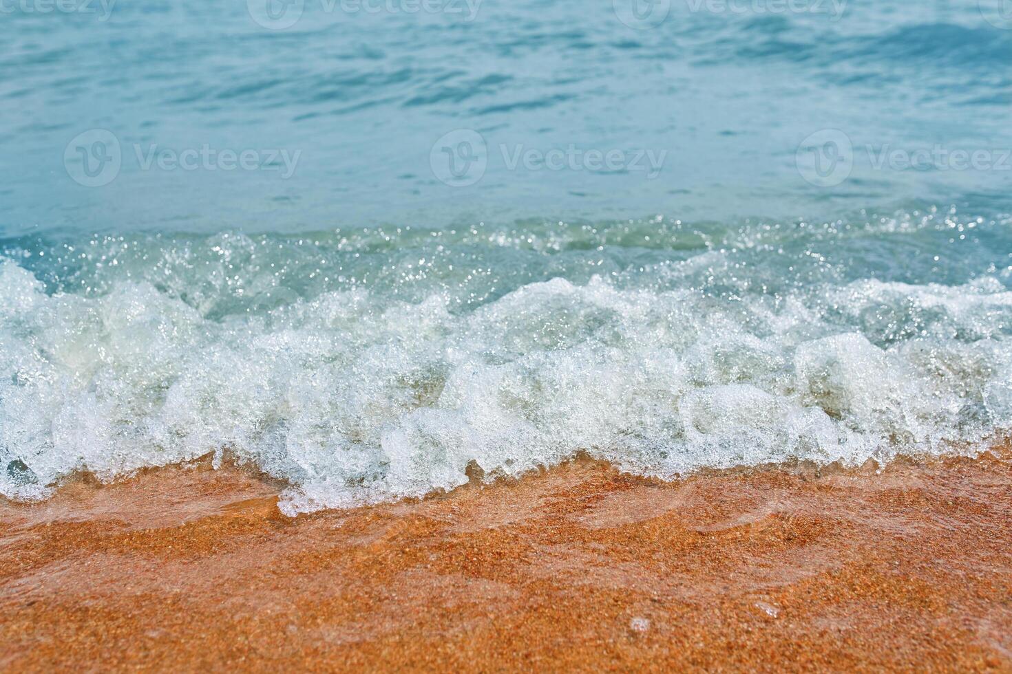 Sandy beach with waves from the sea. Ocean water close up. photo