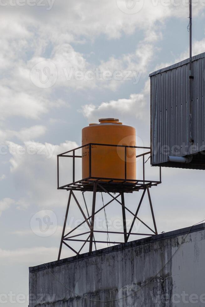 yellow plastic water tank tower on the roof with a clear sky in the background photo