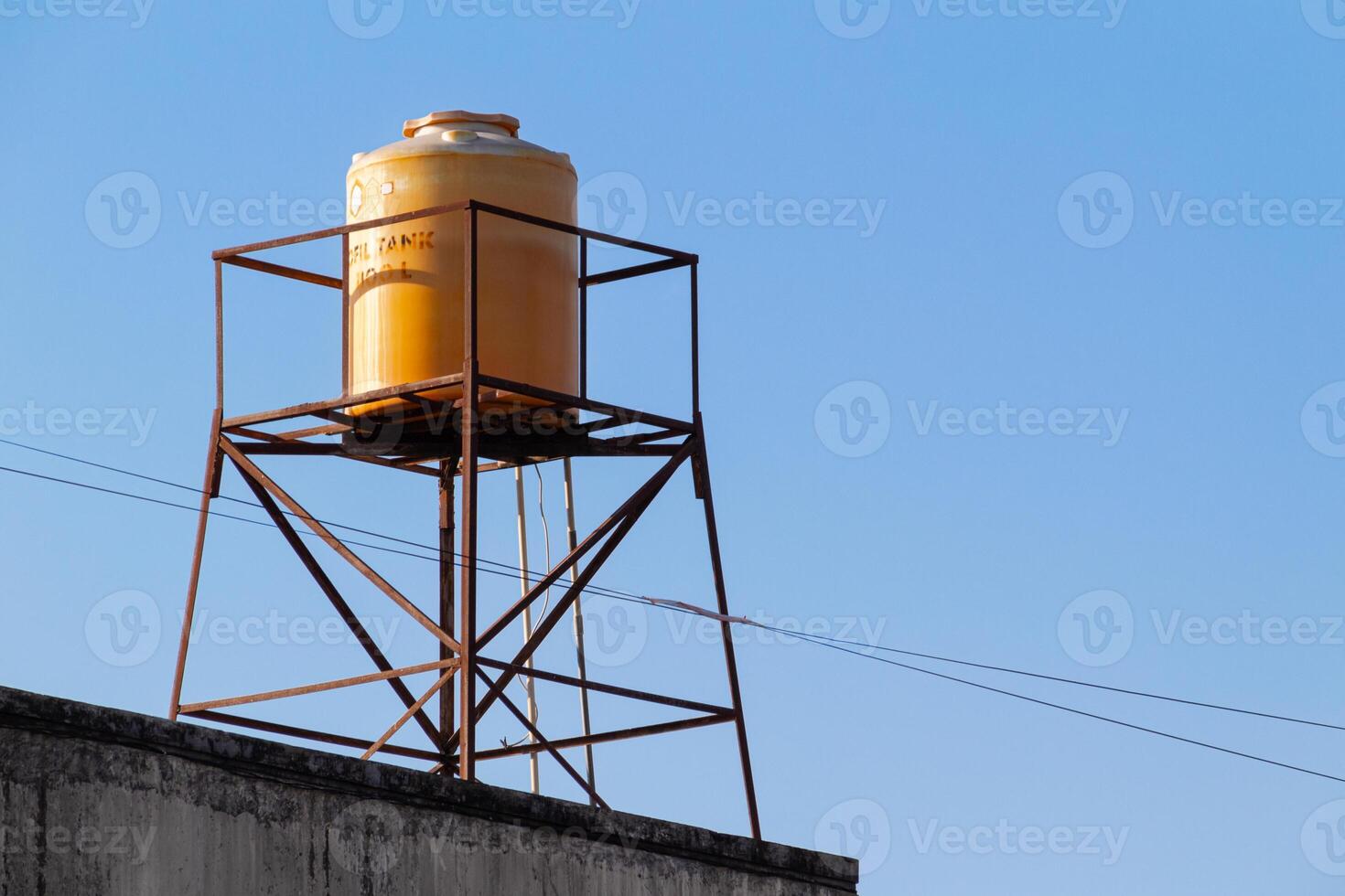 yellow plastic water tank tower on the roof with a clear sky in the background photo