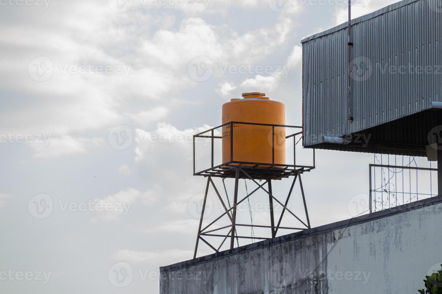 yellow plastic water tank tower on the roof with a clear sky in the background photo