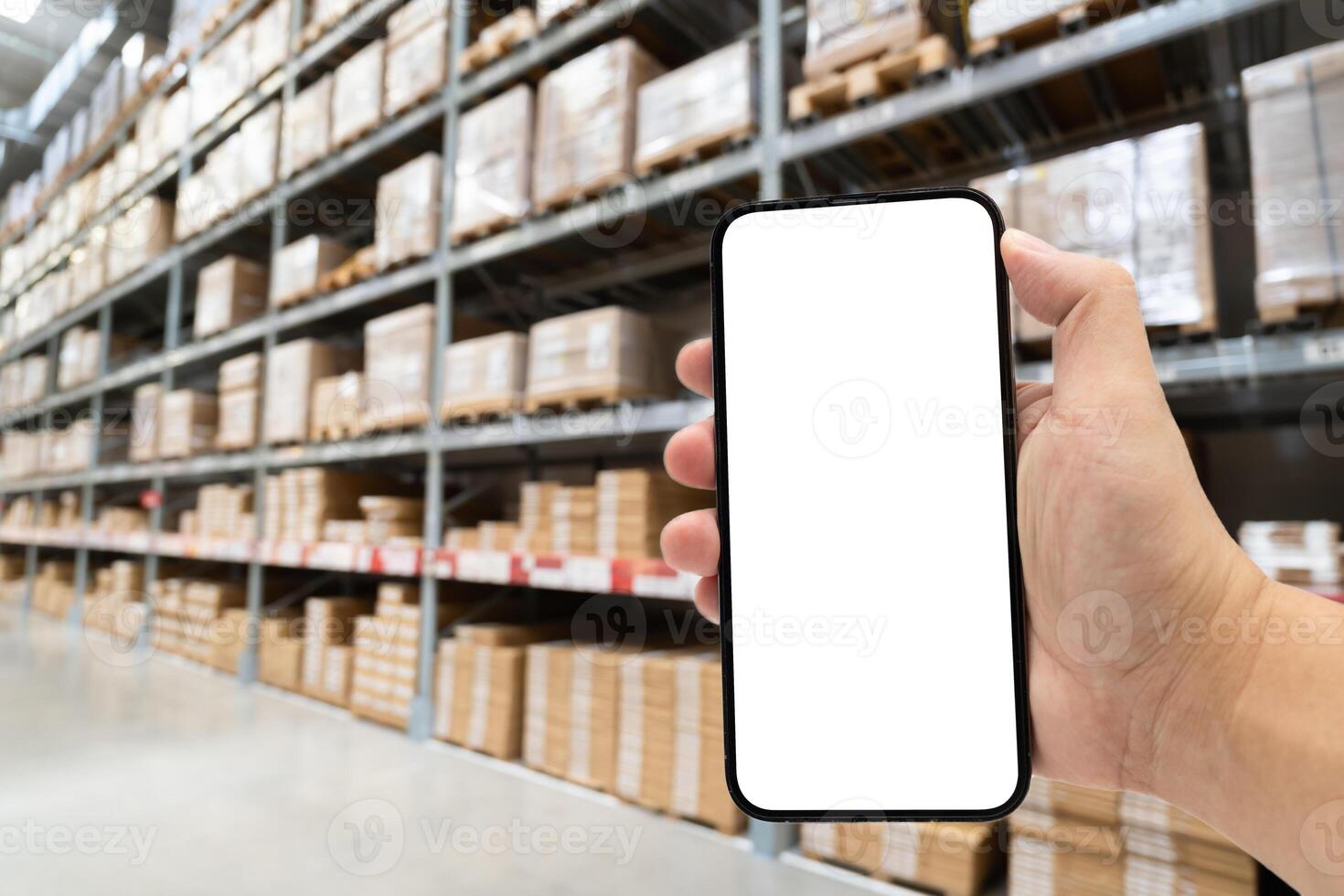 Blank Mobile phone in hand on Blurred large furniture warehouse. Warehouse with a hand holding an empty smartphone. shopping online, pay by phone, Order product. Logistics, business, delivery. photo