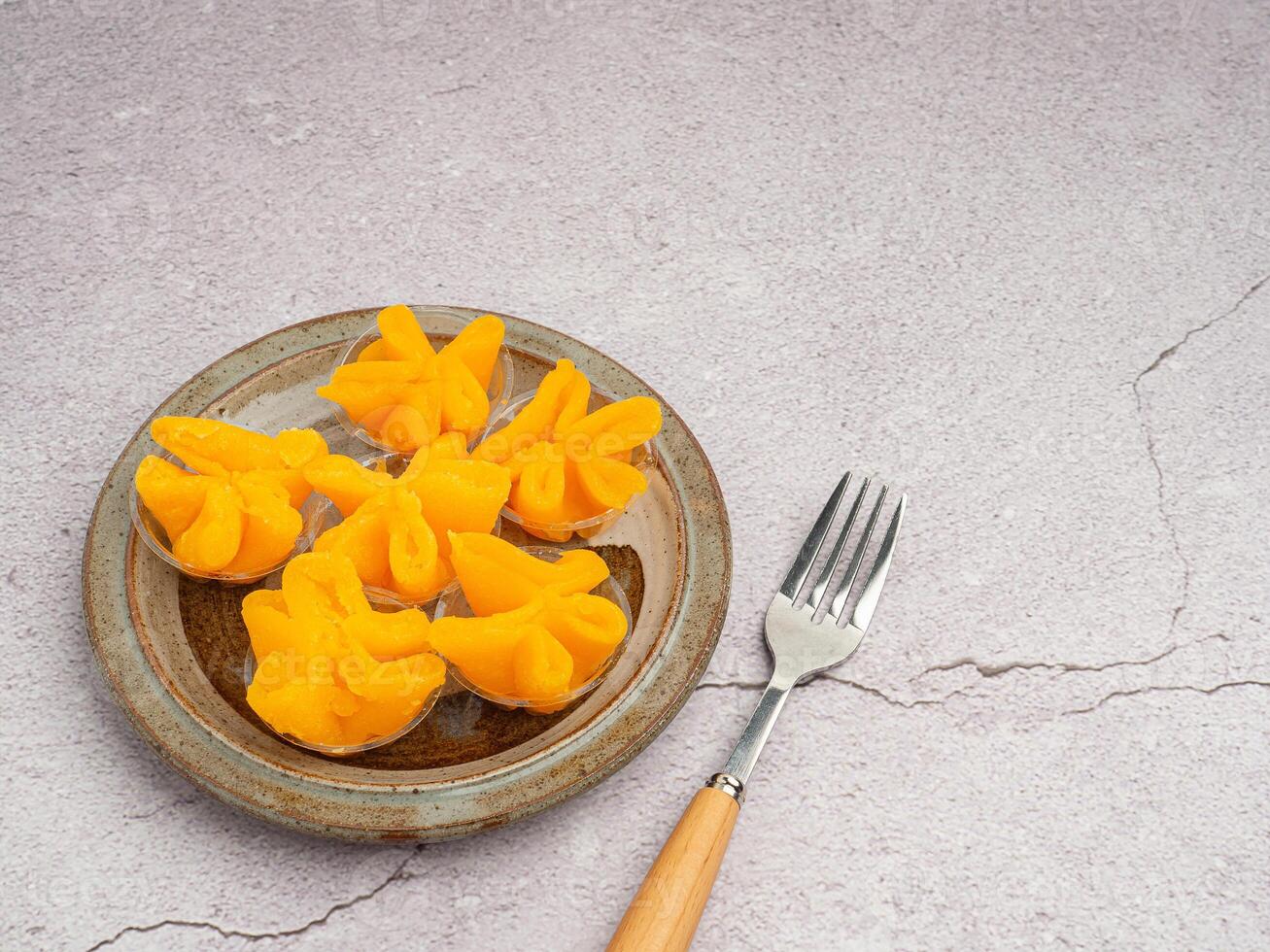 Thai dessert Khanom Thong Yip is placed on a plate with cutlery placed on gray stone background. Space for text. Concept of sweet dessert photo
