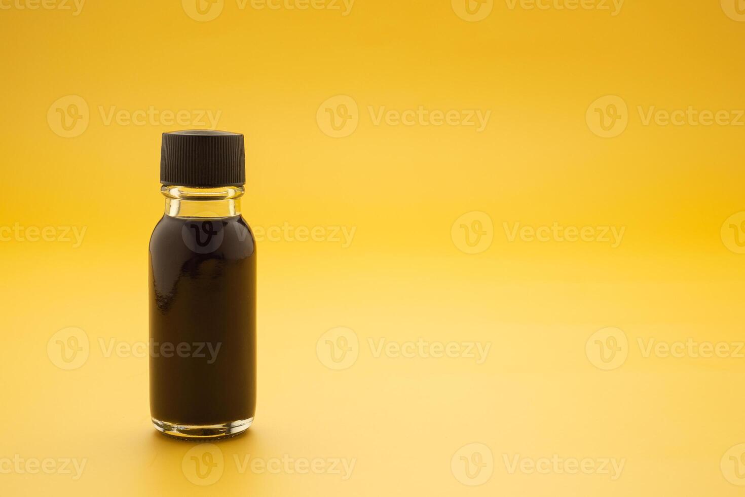 The essential oil in a bottle placed on a yellow background. Space for text. Side view photo