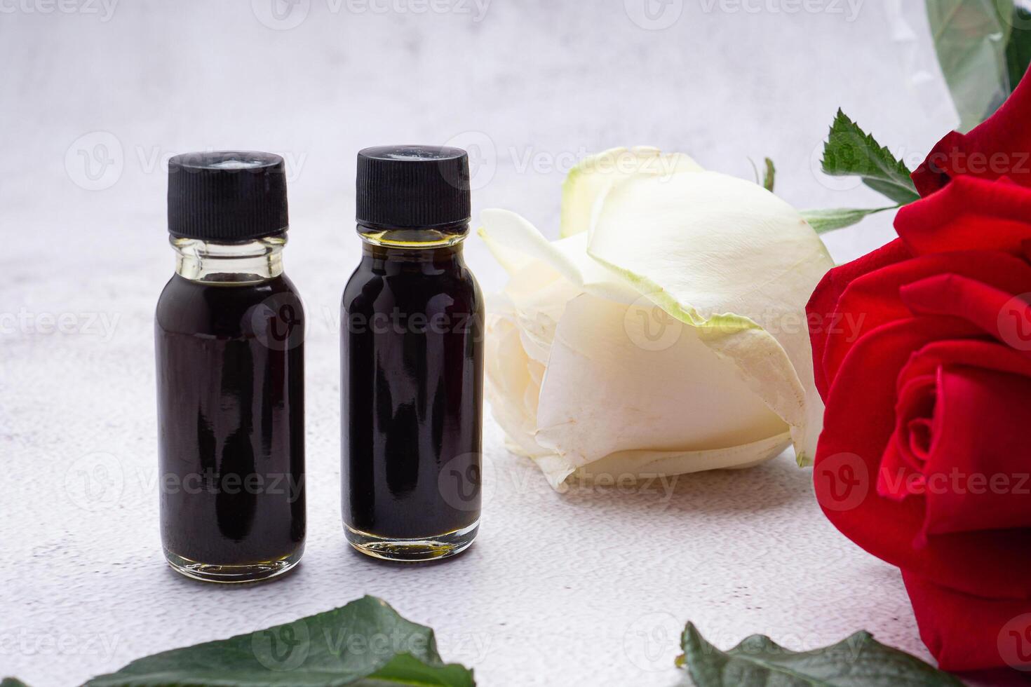 The essential oil in bottles and flowers placed on a gray stone background. Space for text. Side view photo