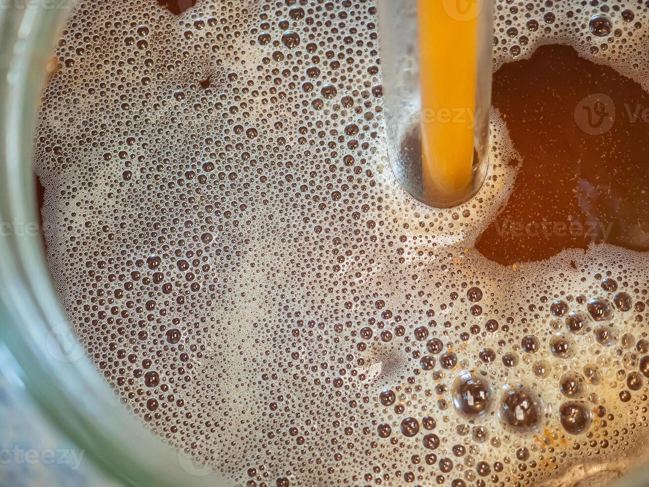 Close-up of craft beer and foam in a fermentation container. Process of making home beer from malt. Craft beer from barley and dark malt photo
