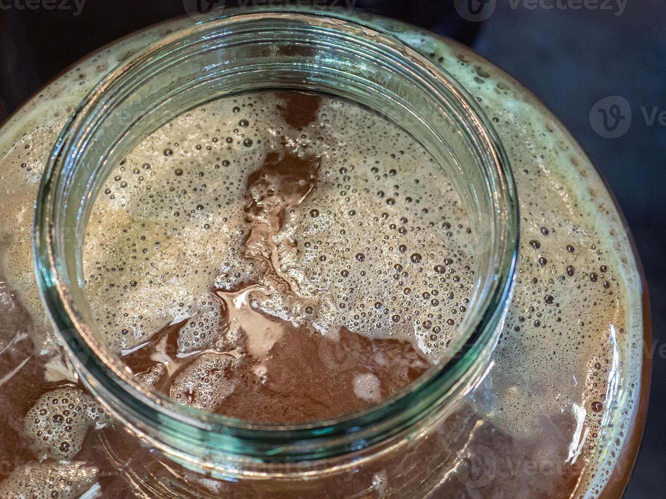 Close-up of craft beer and foam in a fermentation container. Process of making home beer from malt. Craft beer from barley and dark malt photo