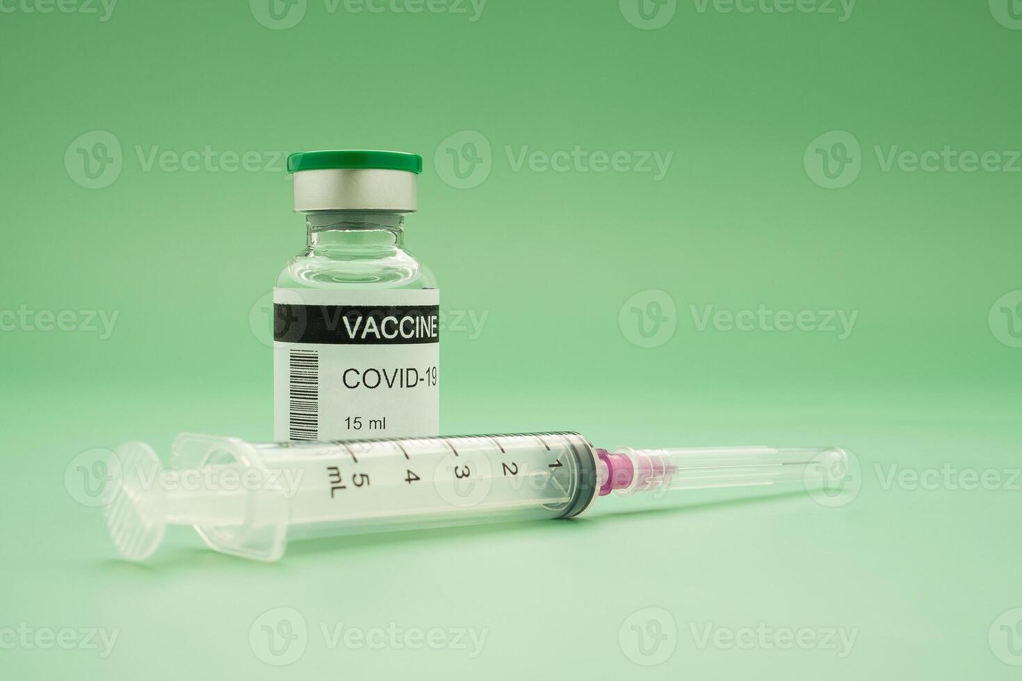 Close-up of a covid-19 vaccine in glass bottles and syringe placed on a green background. Vaccine for prevention, immunization, and treatment from coronavirus infection. Concept of medical photo