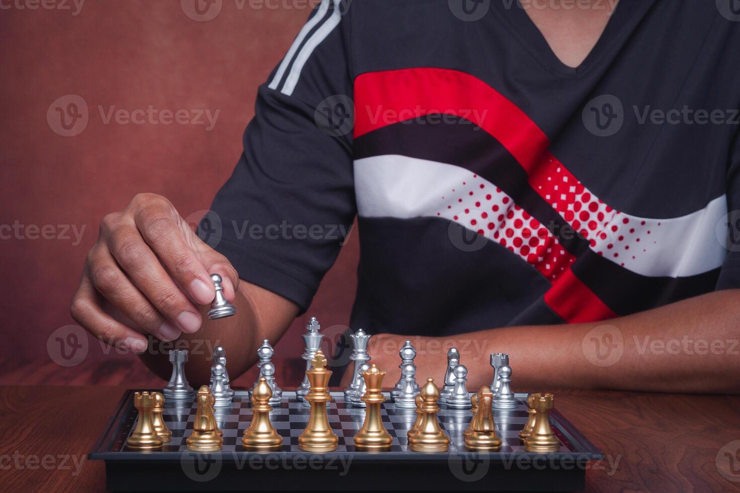 The midsection of playing a game of chess on the chessboard while sitting indoor. The decision on the game. Concept of strategy and planning photo