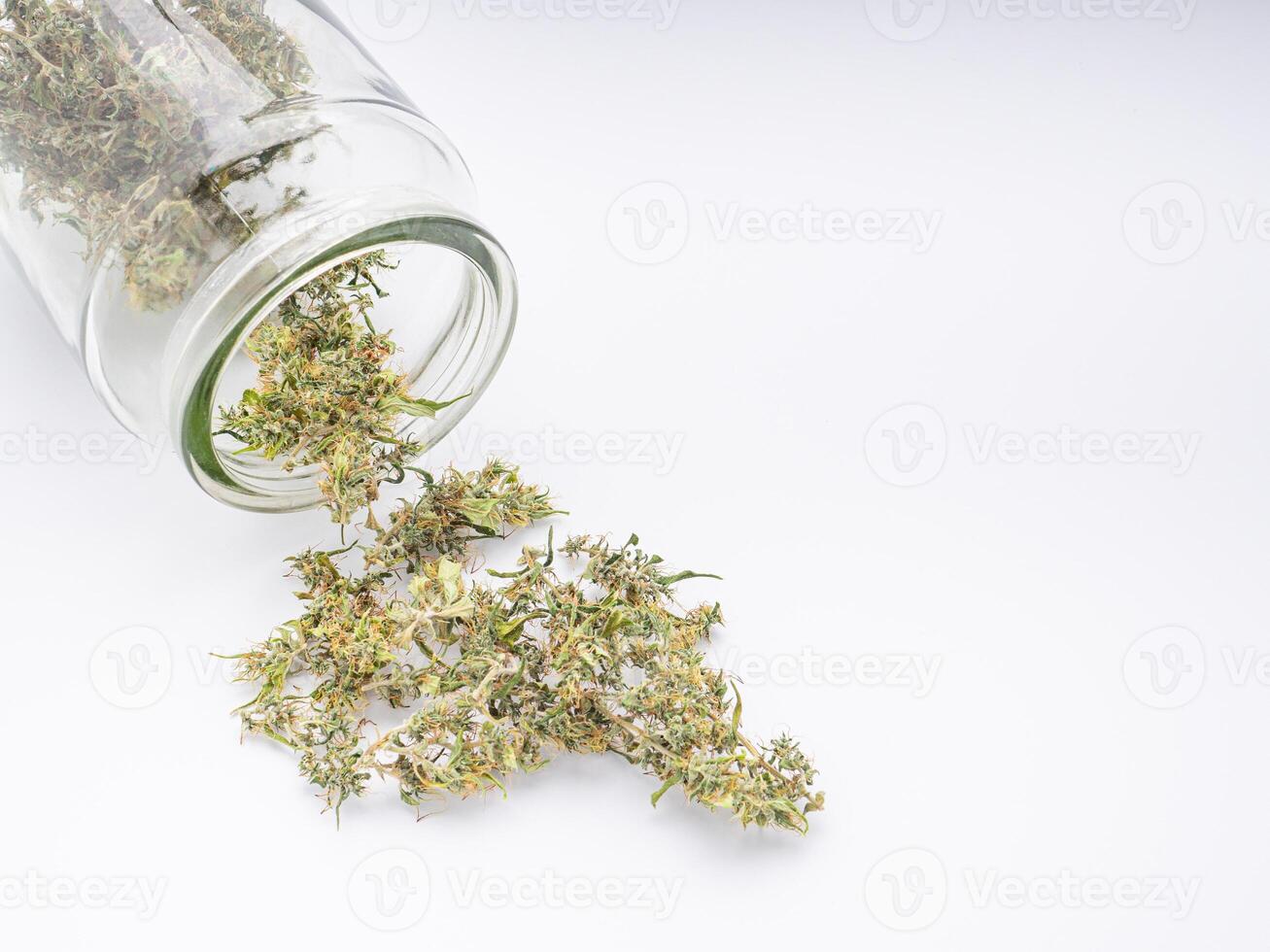 Pouring the cannabis buds out of a container jar glass on white background. The texture of cannabis leaves. Close-up photo with copy space for text. Concept of cannabis plantation for medical