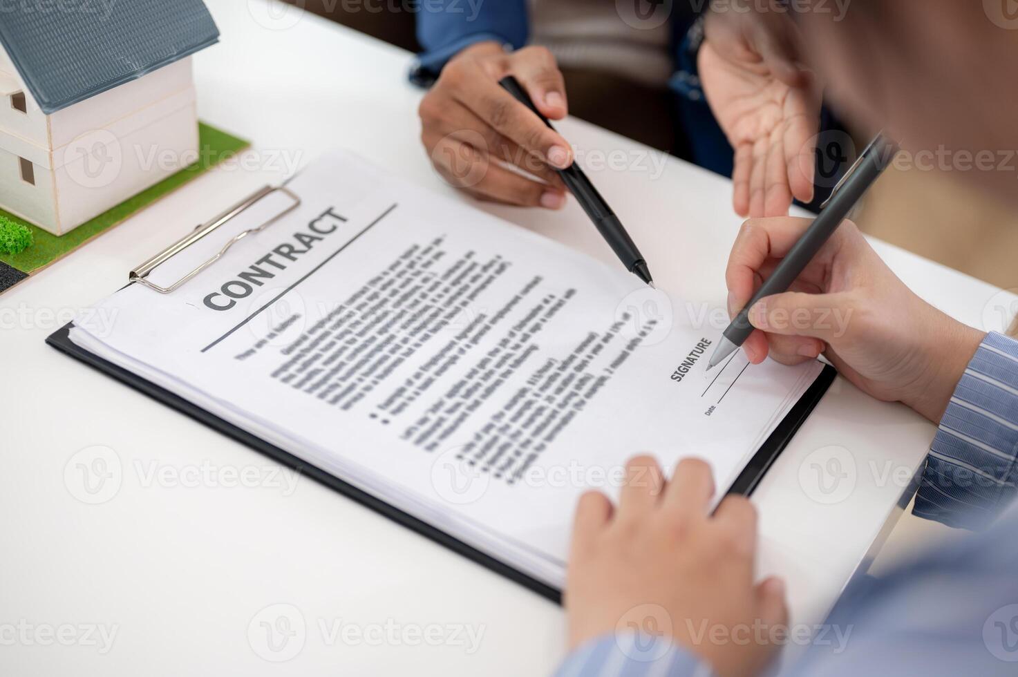A client or buyer signing her signature on a contract during the meeting with her real estate agent. photo