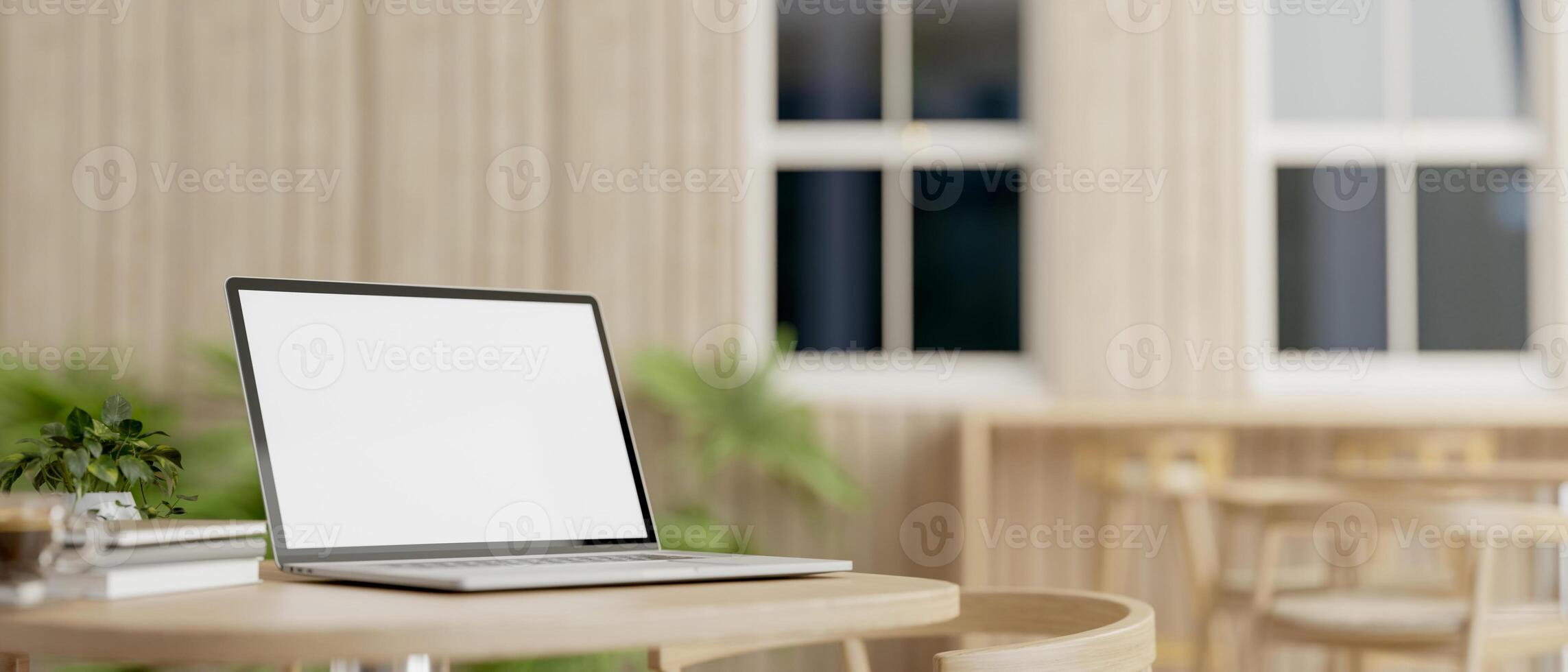 A laptop computer with a white-screen mockup on a table in a comfortable minimalist cafe. photo