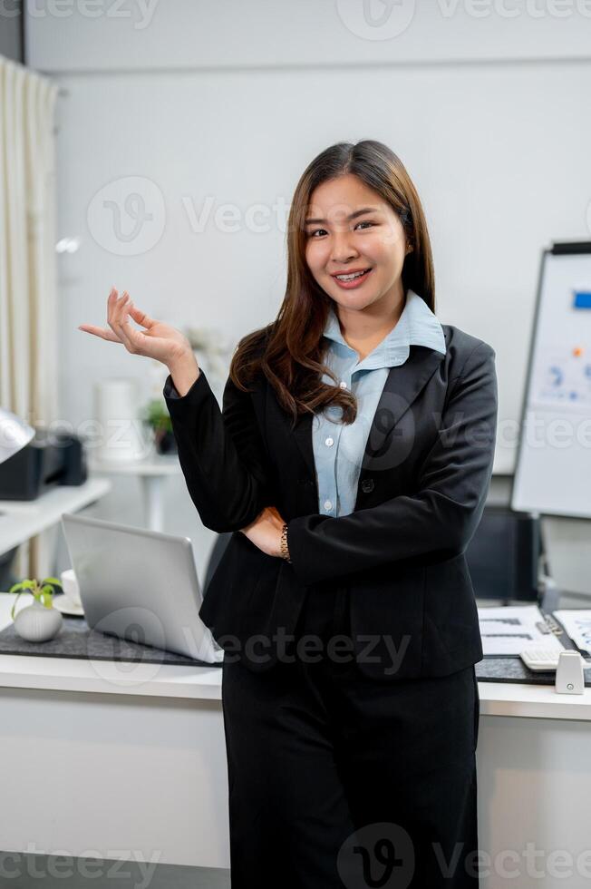 A beautiful, confident Asian businesswoman in a formal business suit is standing in the office. photo
