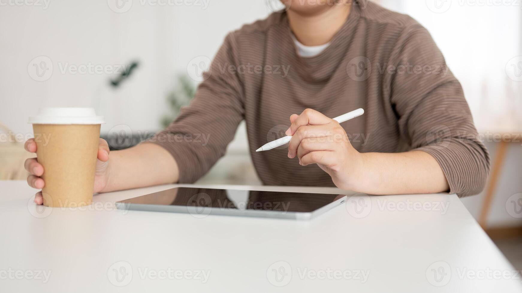 A cropped image of an Asian woman working on her digital tablet in a coffee shop. photo