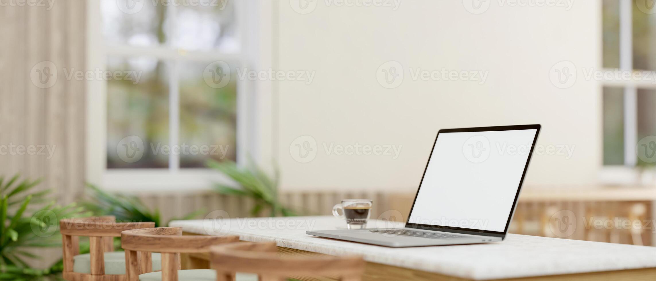 A laptop computer with a white-screen mockup on a table in a comfortable minimalist cafe. photo