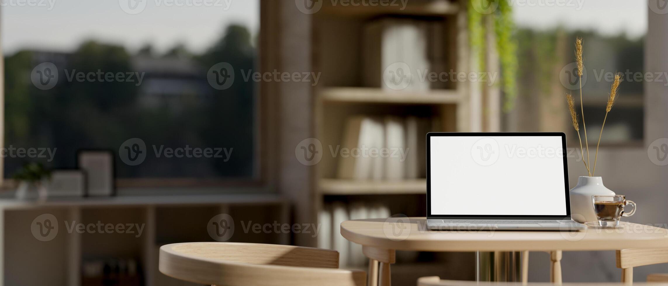 A close-up image of a laptop computer with a white-screen mockup on a wooden table in a cozy room. photo