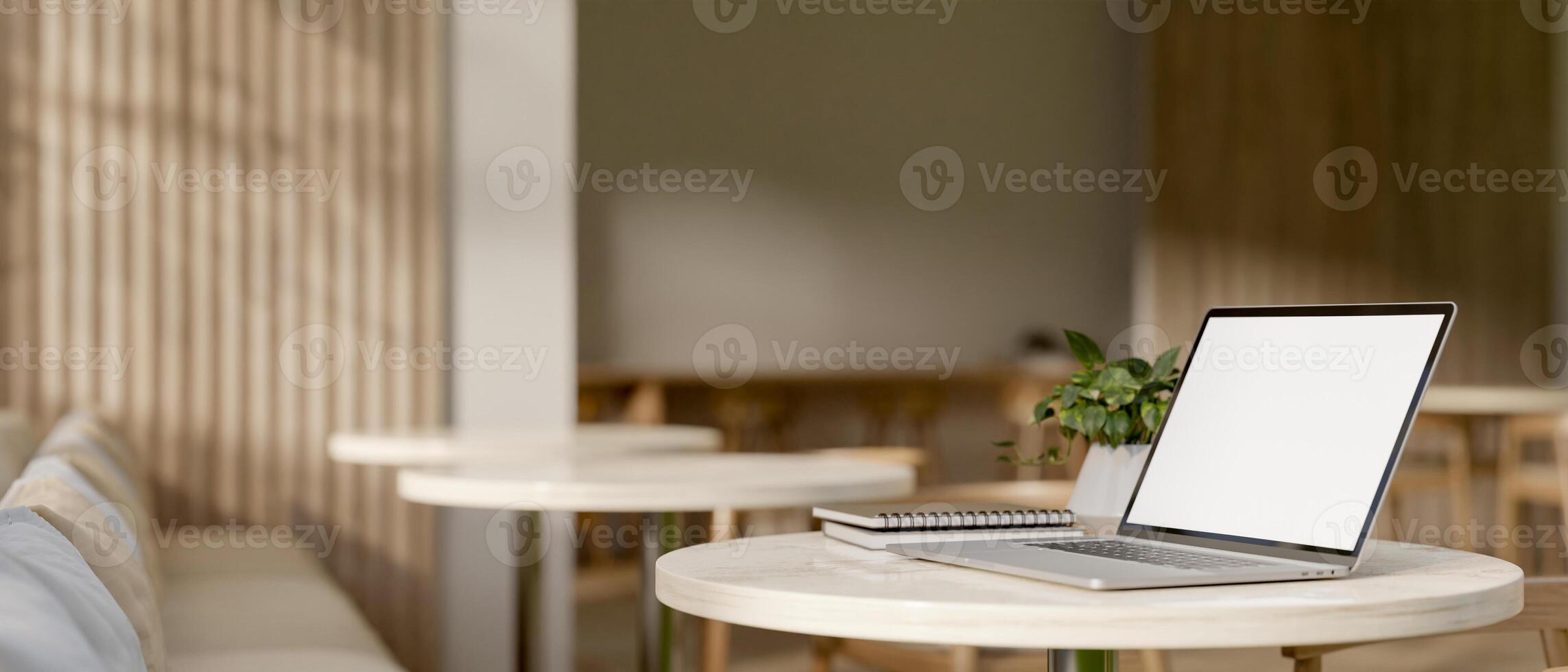 A laptop computer with a white-screen mockup on a table in a modern, comfortable coffee shop. photo