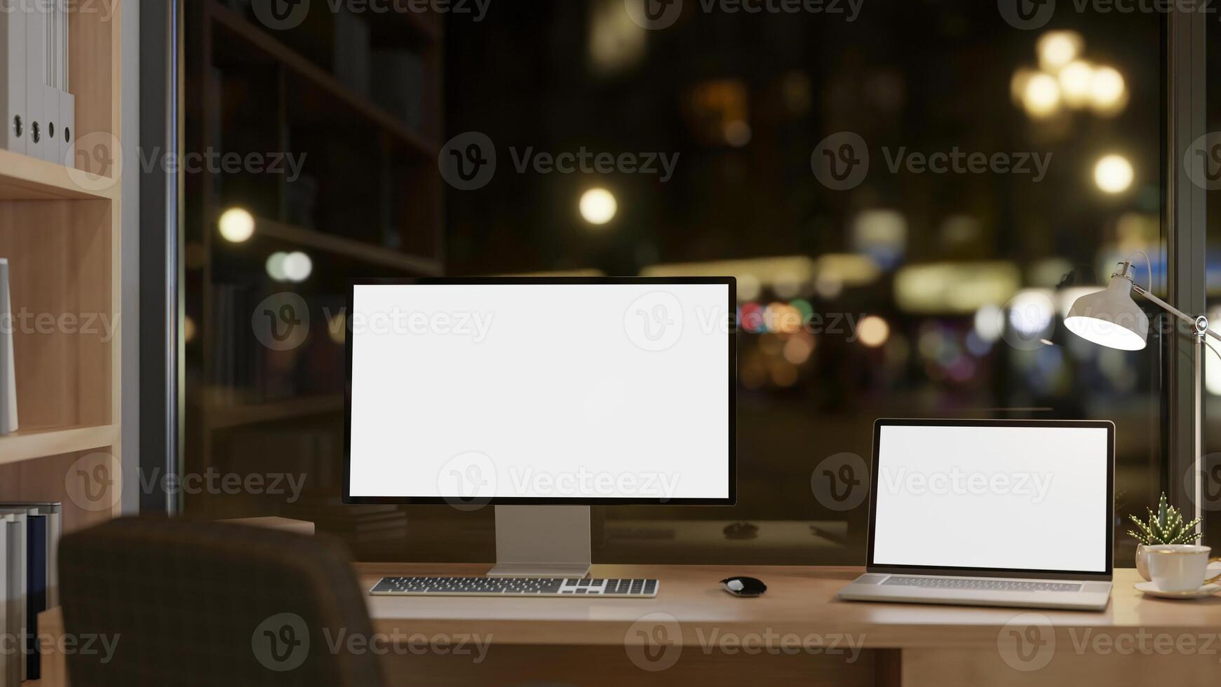 A modern private office at night features a computer and a laptop with white-screen mockup on a desk photo