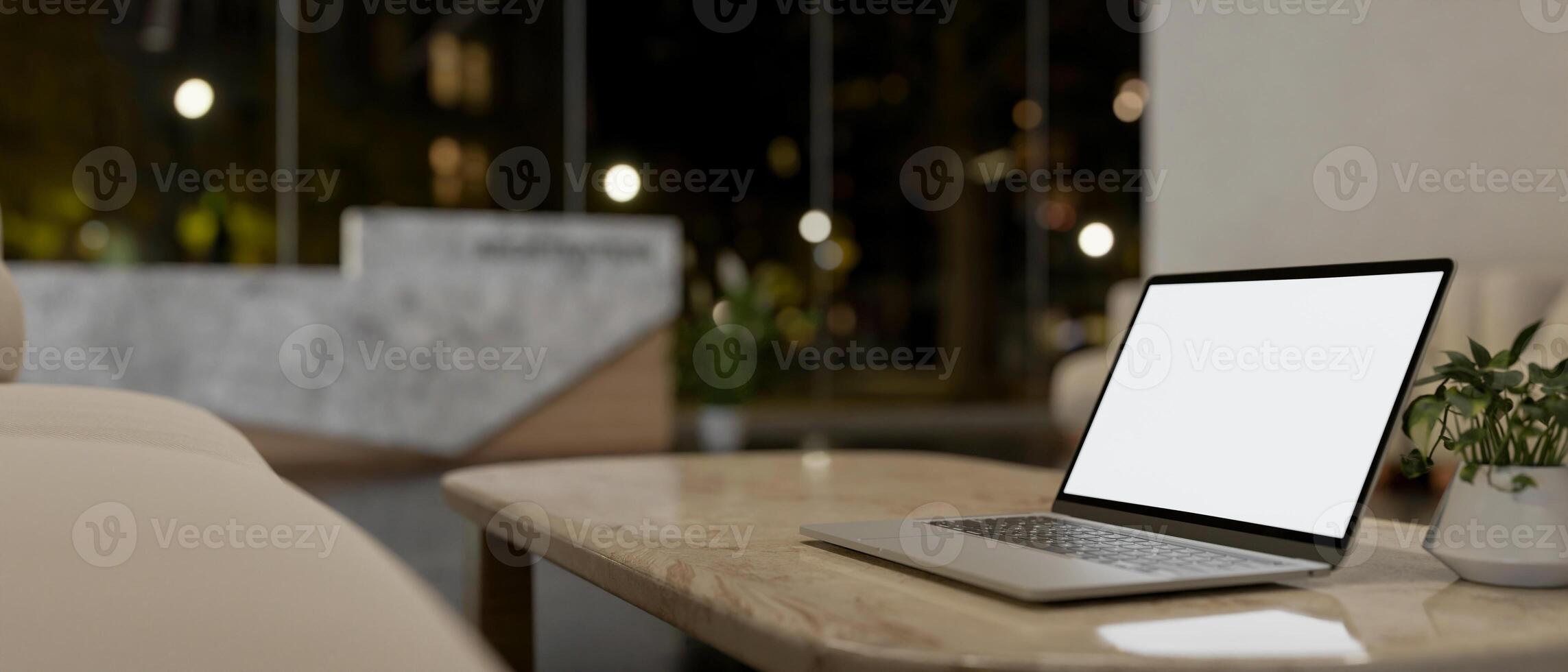 A laptop computer on a neutral marble coffee table in a modern lobby lounge at night. photo