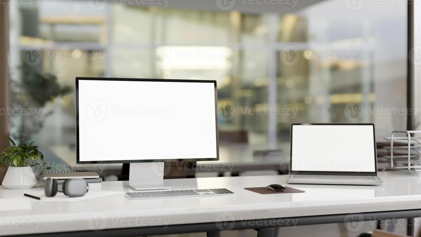 A computer desk in a modern office room features a computer and a laptop with white-screen mockup. photo
