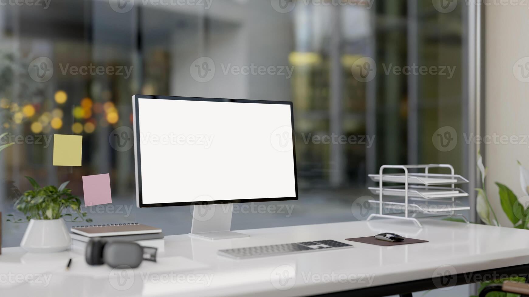 A modern office features a computer with a white-screen mockup and office supplies on a white desk. photo