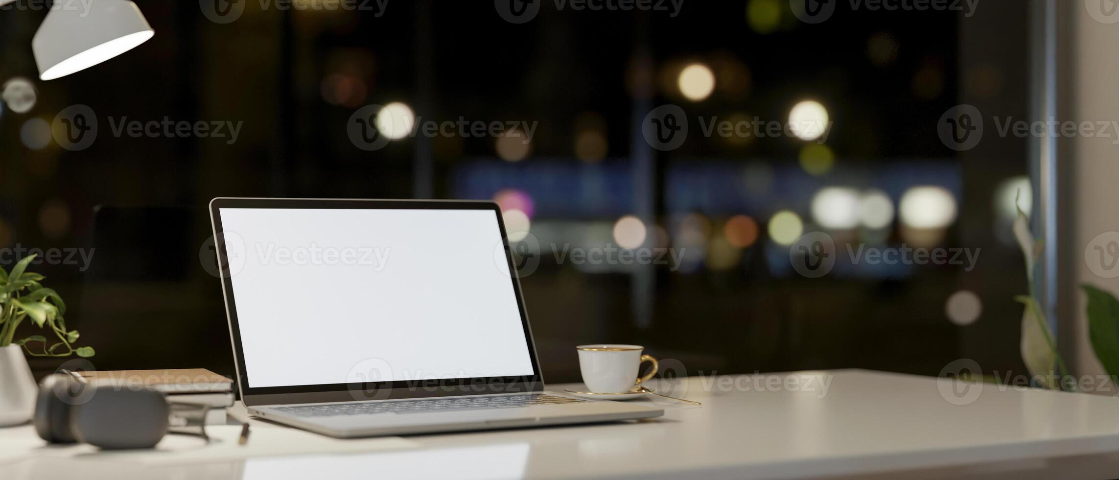 A laptop computer and accessories on a table against the window with a night city view. photo