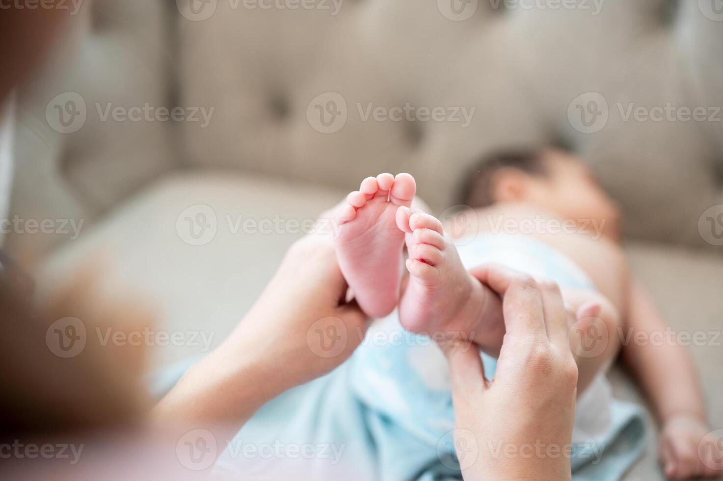 A close-up image of a mom lifting her newborn baby's legs up to change his diaper and put clothes on photo