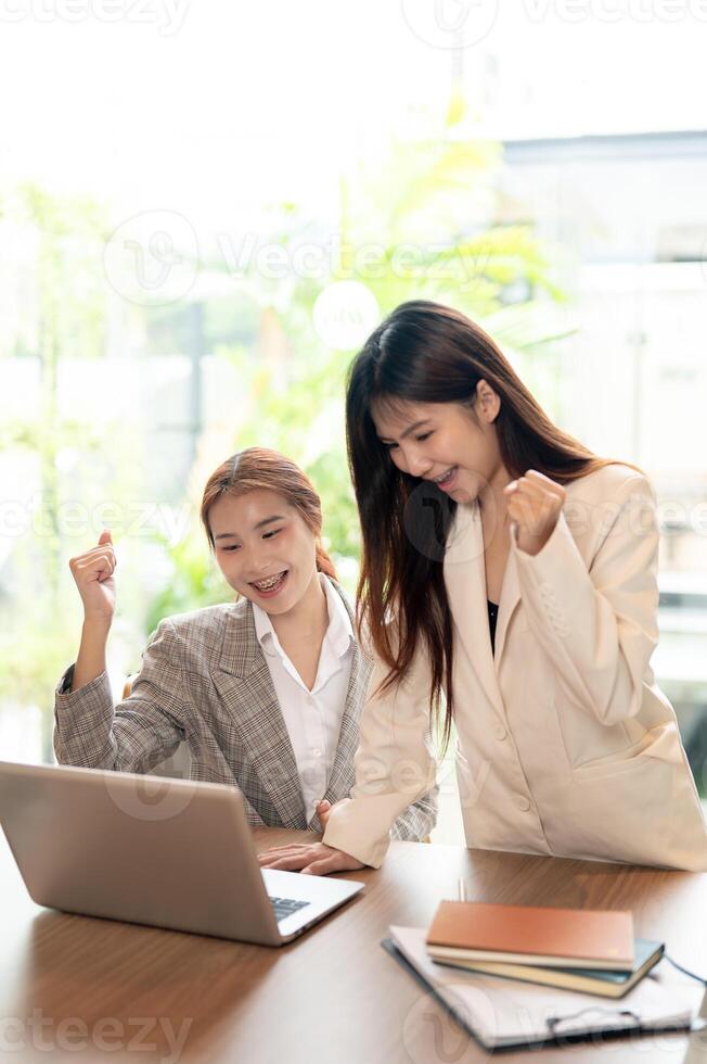 Two cheerful Asian businesswomen are celebrating their business project success together. photo