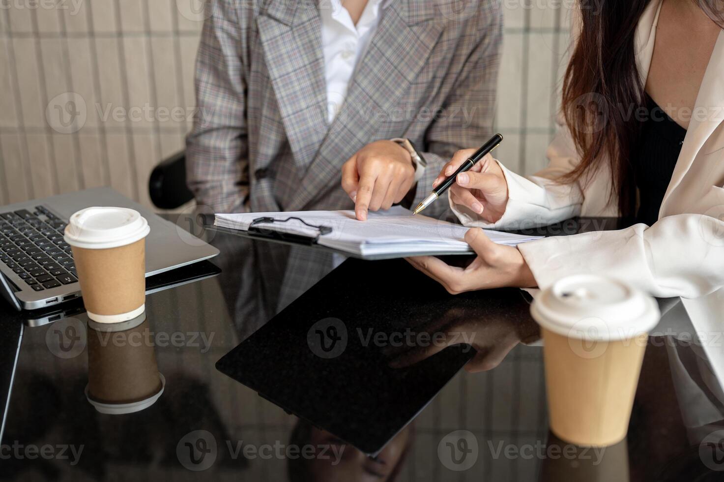 A cropped image of two businesswomen are checking the documents and working together. photo