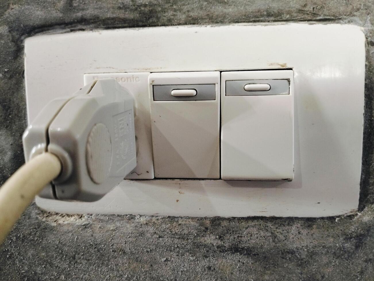 Old electrical plastic plug and old switch on the wall in home photo
