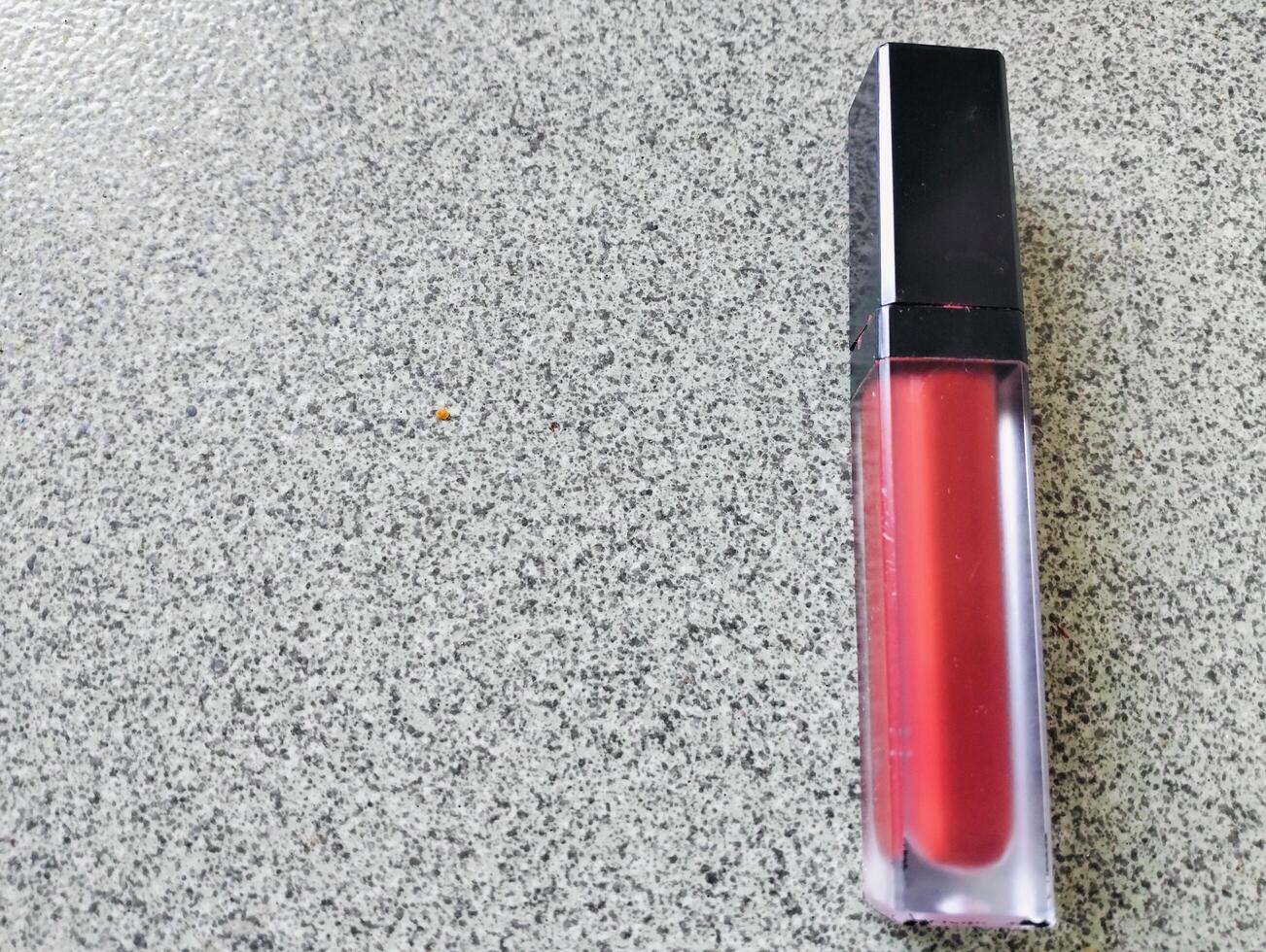 Red lip cream liquid lipstick and applicator, top view of creamy red lip cream with an elongated tube container photo