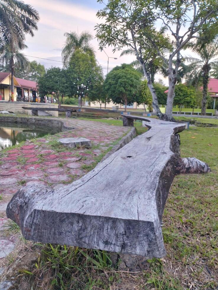 Wooden bench in the park or garden next to the pool, creative interior chair design that can be useful for sitting, relaxing and resting, Beautiful nature background. photo