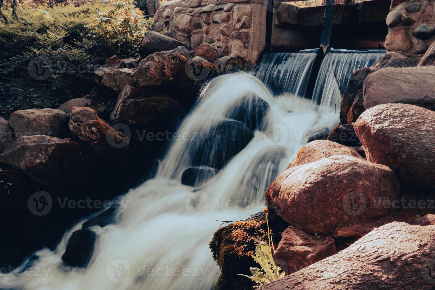 Waterfall cascade in Olivia public park Gdansk Poland. River waterfall falls from cliff and trees. Tourist attraction with small waterfall and clear water Long exposure Unity with nature photo
