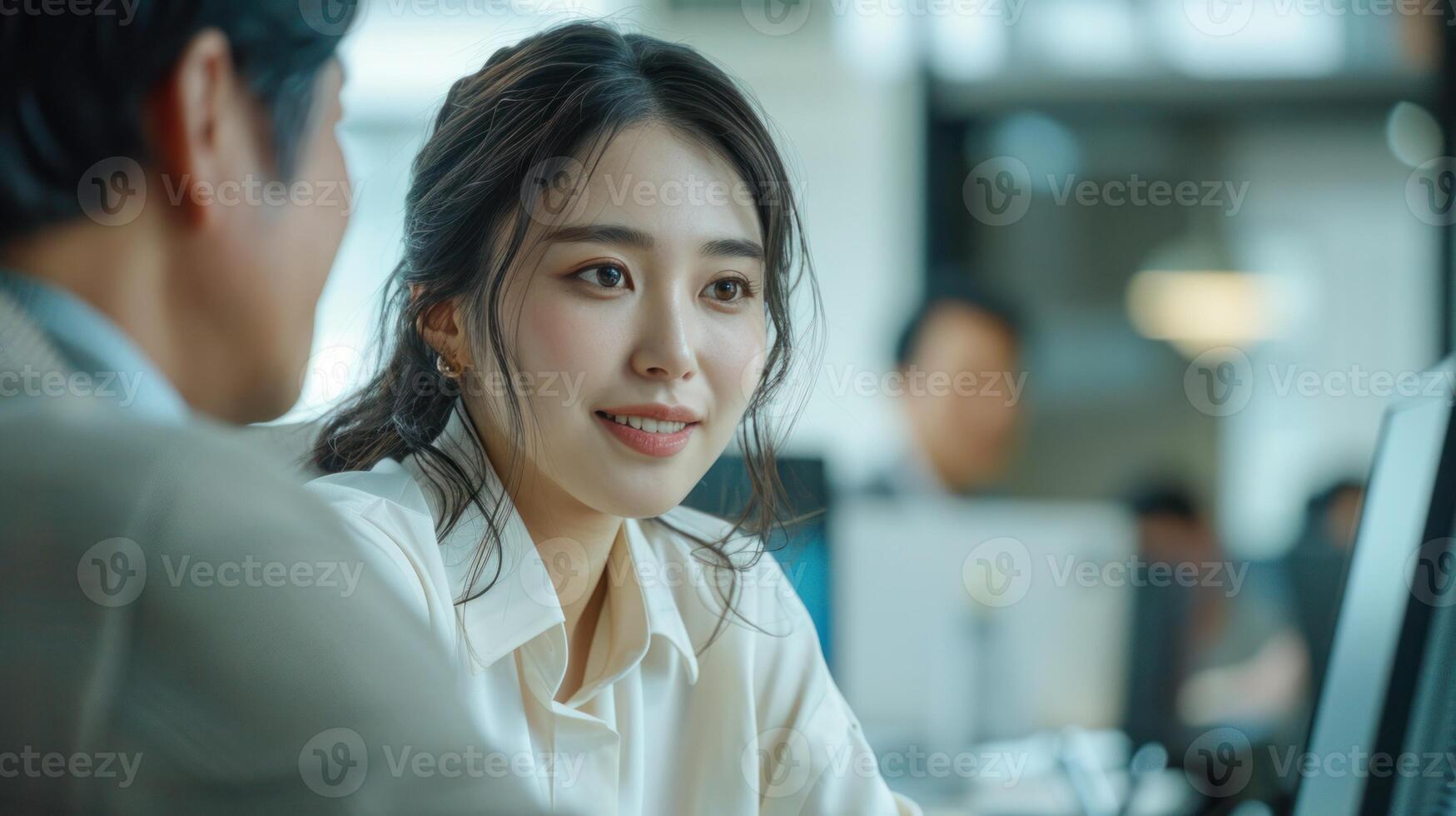 Professional Asian businesswoman discussing work with a colleague in a modern office setting, reflecting teamwork and collaboration. photo