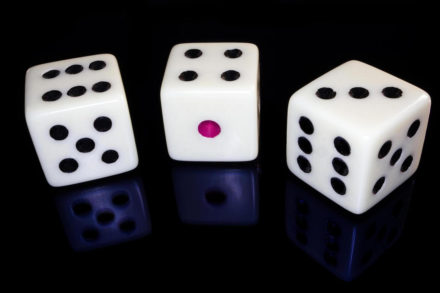 Three white dices isolated on black reflective background photo