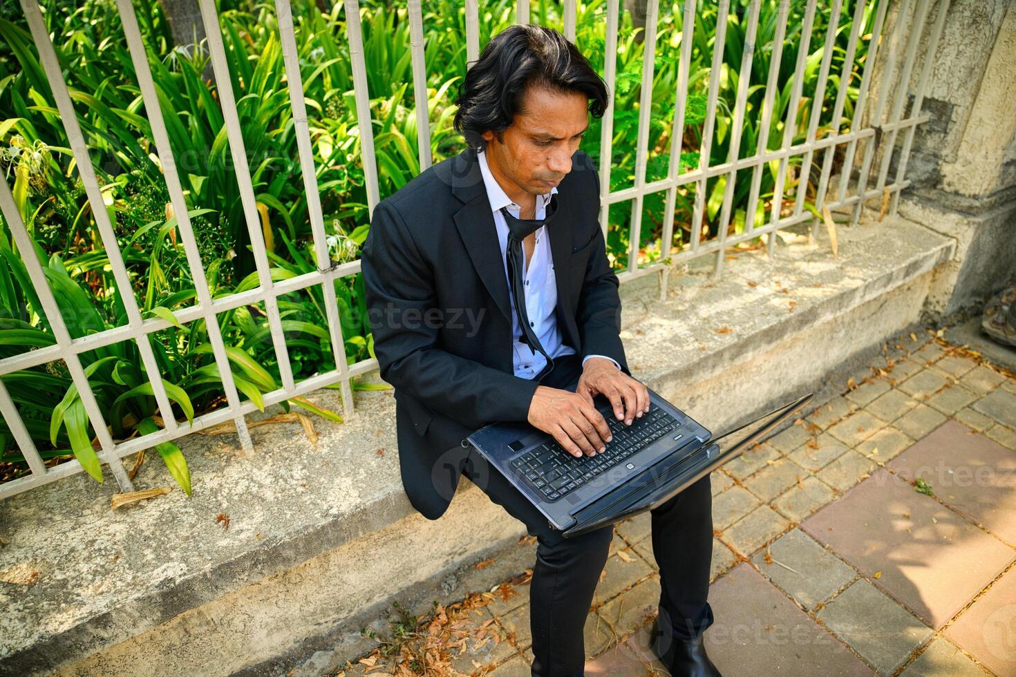 Man working on a laptop with a concerned expression photo